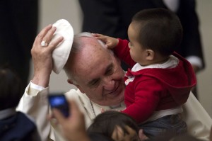 Pope Francis has his skull cap removed by a child during an audience with children in the Vatican